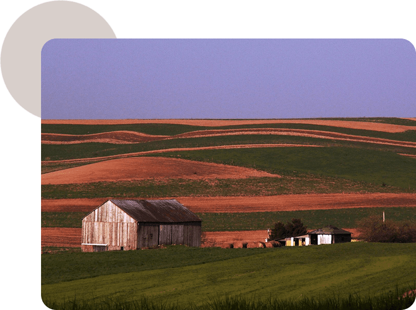 A barn and some buildings in the middle of an open field.