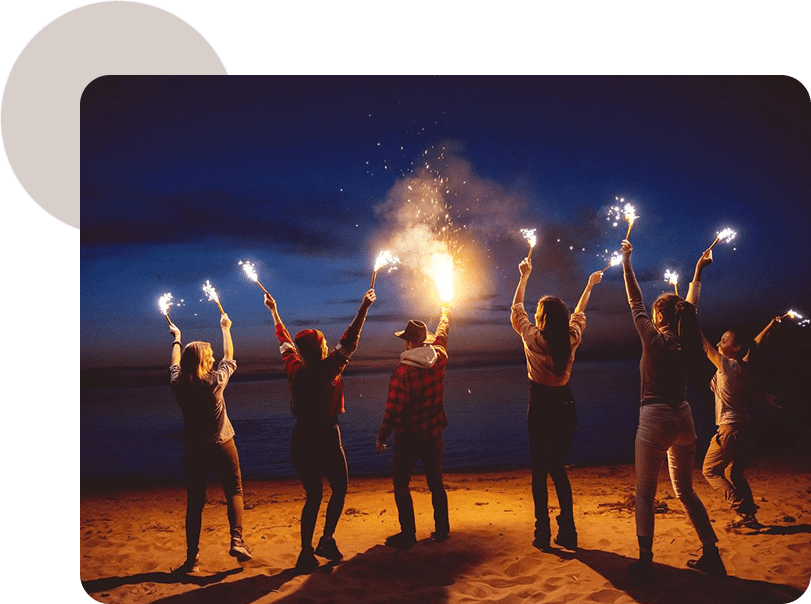 A group of people holding sparklers on the beach